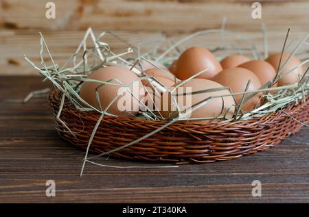 Fresh chicken brown eggs with hay on a wicker basket Stock Photo