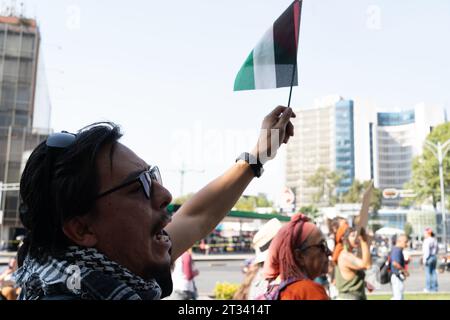 Pro-Palestine march, Mexico City, Mexico. 22nd Oct, 2023. a man holding a Mexican Communist Party flag and wearing a keffiyeh chants at the march. Thousands of people protest in Mexico City, whilst repeatedly chanting ÕItÕs not a war. ItÕs Genocide'. Many people waved Palestinian flags, others wore a keffiyeh in solidarity with the people of Palestine. Various groups formed part of the march including the Mexican Communist Party, pro-abortion activists and LGBTQ  groups. Credit: Lexie Harrison-Cripps/Alamy Live News Stock Photo