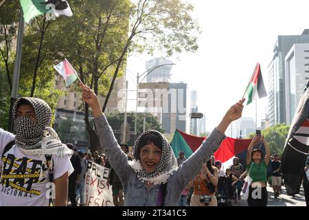 Pro-Palestine march, Mexico City, Mexico. 22nd Oct, 2023. a protester wearing a keffiyeh holds two Palestinian flags. Thousands of people protest in Mexico City, whilst repeatedly chanting ÕItÕs not a war. ItÕs Genocide'. Many people waved Palestinian flags, others wore a keffiyeh in solidarity with the people of Palestine. Various groups formed part of the march including the Mexican Communist Party, pro-abortion activists and LGBTQ  groups. Credit: Lexie Harrison-Cripps/Alamy Live News Stock Photo