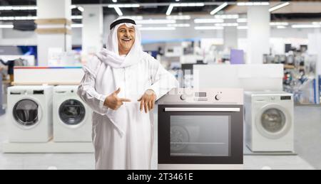 Mature arab man standing in a shop with washing machines and leaning on an oven Stock Photo