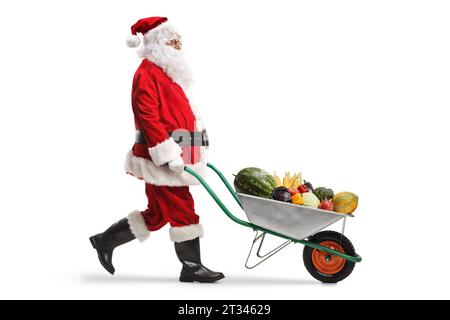 Santa claus walking and pushing fruits and vegetables in a wheelbarrow isolated on white background Stock Photo