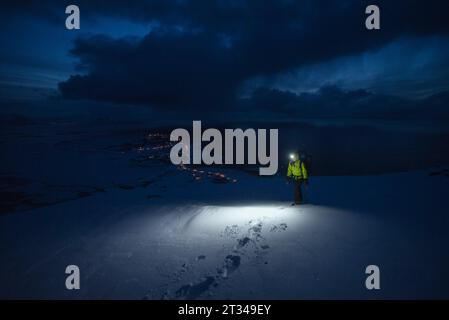 Woman hiking at night with headlamp at Matmora, Delp, Astvagoya, Lofoten, Norway Stock Photo