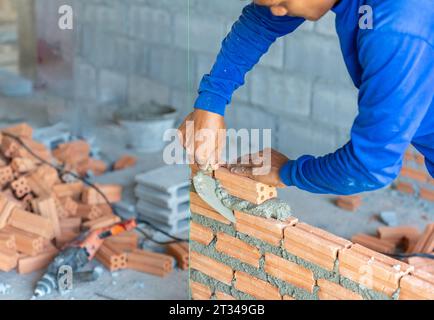 Bricklayer industrial worker installing brick masonry with trowel putty knife at construction site Stock Photo