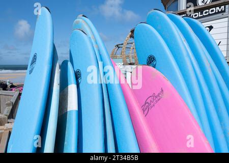 Colourful surfboards stacked and available to hire at the surf hire shop at Fistral Beach in Newquay in Cornwall in England in the UK. Stock Photo