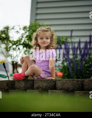 Little girl smiling in flower garden Stock Photo