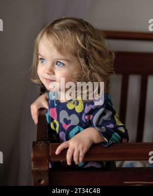 Beautiful toddler with blue eyes standing in crib Stock Photo