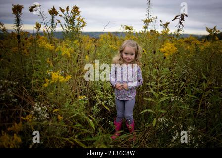 Little girl smiling in field of wildflowers with pink boots Stock Photo