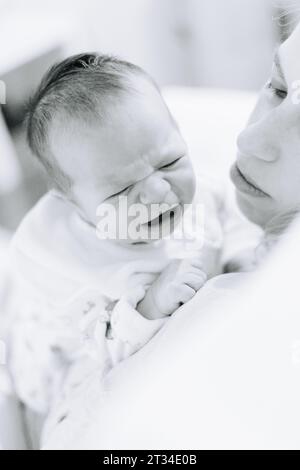 One week old newborn baby crying on his mothers shoulder Stock Photo