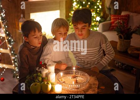 Three children, lighting candles in a nutshell, czech Christmas traditions, decorated room, family traditions Stock Photo
