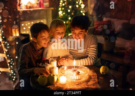 Three children, lighting candles in a nutshell, czech Christmas traditions, decorated room, family traditions Stock Photo
