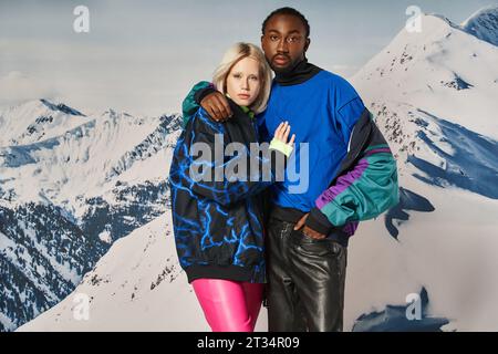 attractive interracial couple in stylish outfits hugging and looking at camera, winter concept Stock Photo