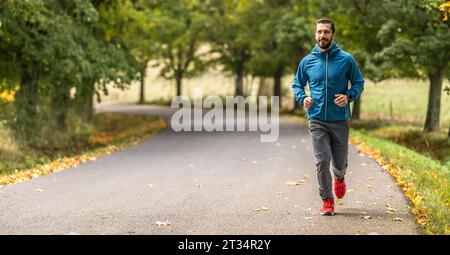 A young man is training and running in an autumn park. Stock Photo