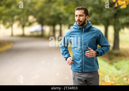 A young man is training and running in an autumn park. Stock Photo