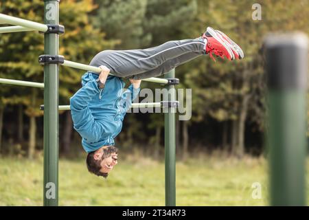 Young man working out calisthenics in an outdoor gym using parallel bars. A good looking athlete is doing gymnastic exercises on an outdoor sports fie Stock Photo