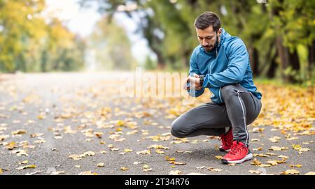 A good-looking athlete puts on his sports watch before running. Copy space on the left side. Stock Photo