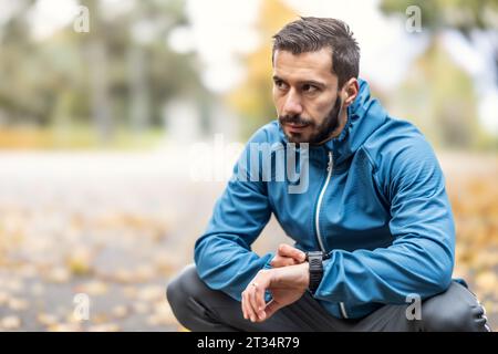 A good-looking sportsman checks the measured values on a sports watch and rests. Stock Photo