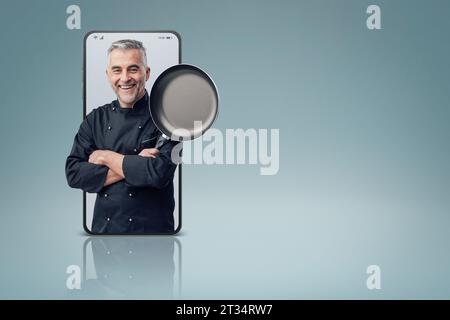 Confident smiling successful chef posing in a smartphone videocall and smiling, online  service concept Stock Photo