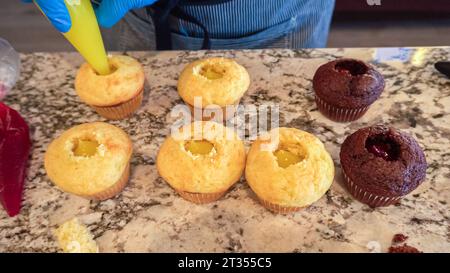 Filling Vanilla, Chocolate Cupcakes with Lemon, Raspberry Stock Photo