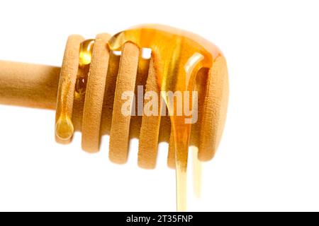 Liquid and fresh honey dripping from wooden honey spoon white background Stock Photo