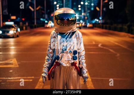 Spaceman standing on a street in the city at night Stock Photo