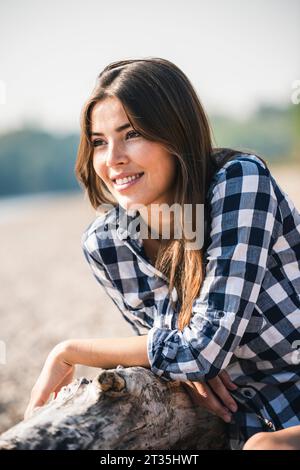 Smiling young woman sitting outdoors Stock Photo