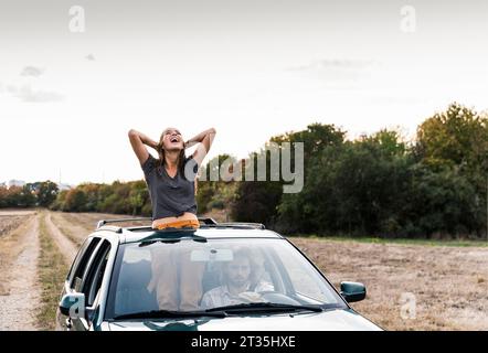 Carefree young woman looking out of sunroof of a car Stock Photo