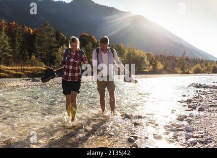 Austria, Alps, couple on a hiking trip wading in a brook Stock Photo