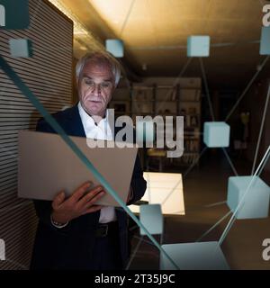 Digital composite image of businessman using laptop in office Stock Photo