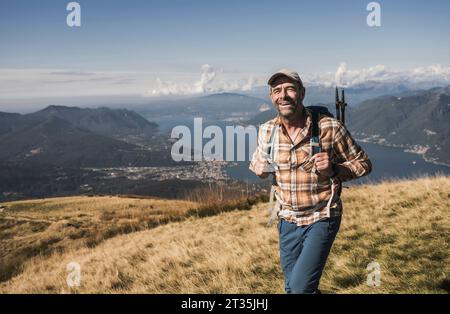 Happy man enjoying hiking on mountain at sunny day Stock Photo