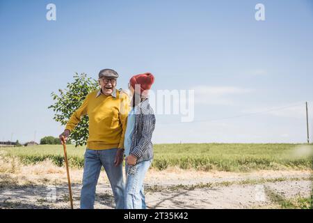 Cheerful senior man walking with granddaughter on road Stock Photo