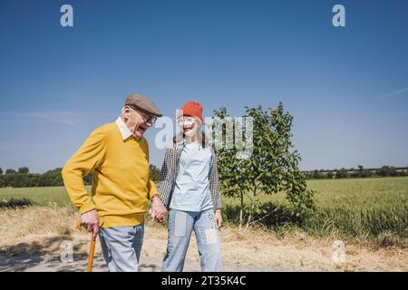 Happy senior man holding hands and walking with granddaughter Stock Photo