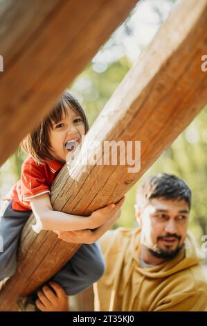 Cheerful boy having fun hanging on log Stock Photo