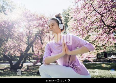 Teenage girl with hands clasped practicing yoga at park in bloom Stock Photo