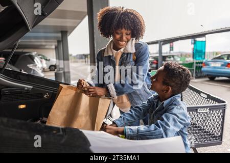 Happy mother and son keeping shopping bags in car trunk Stock Photo