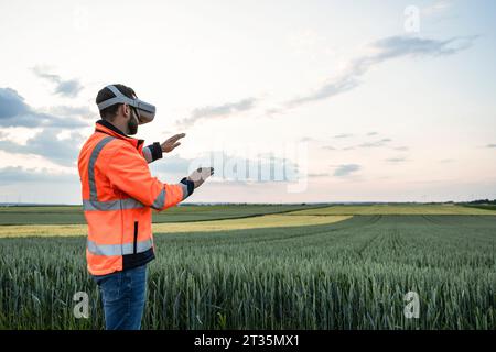 Engineer wearing virtual reality headset in field Stock Photo