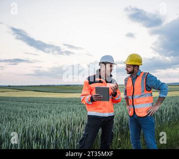 Engineers with tablet PC discussing at field Stock Photo