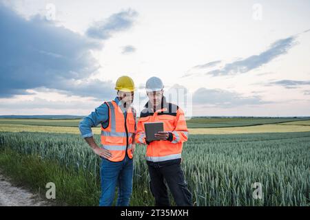 Engineers using tablet PC discussing at field Stock Photo
