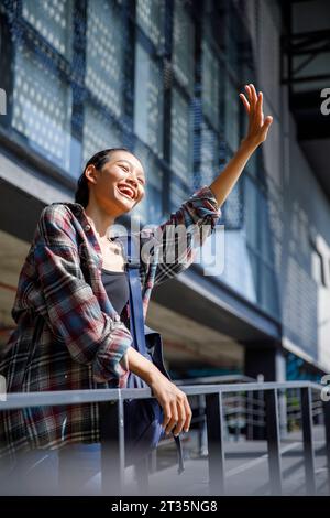 Smiling student waving in university Stock Photo