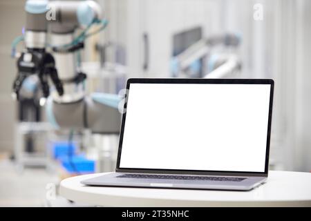 Laptop with blank screen on table in factory Stock Photo