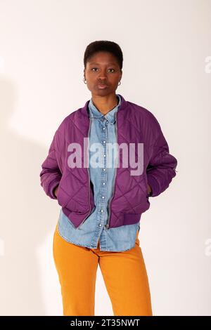 Young woman with hands in pockets standing against white background Stock Photo