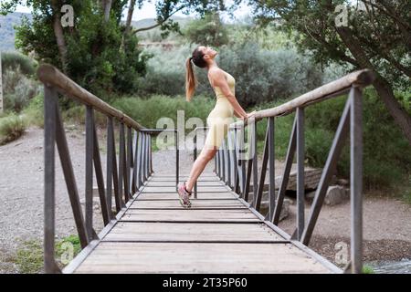 Woman stretching on bridge in forest Stock Photo