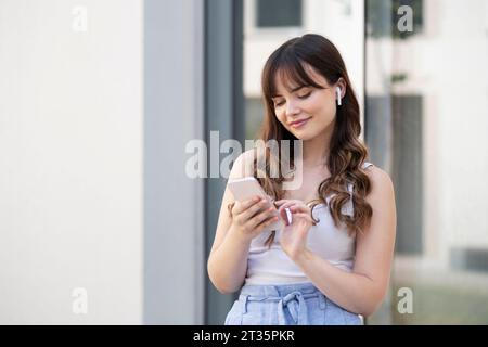 Smiling young woman using mobile phone Stock Photo
