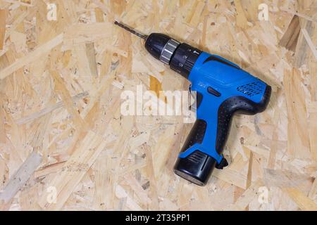 Close up of electric drill and drill bits on old wooden table. On left side is empty space to put text or something else. This file is cleaned and ret Stock Photo