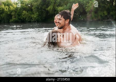 Cheerful father having fun with sons in water Stock Photo