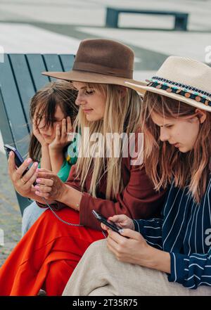 Mother and daughter using mobile phone on bench Stock Photo