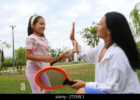 Happy mother giving high-five to daughter in park Stock Photo