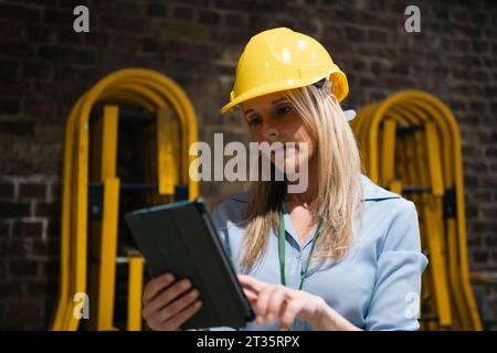 Blond engineer using tablet PC at factory Stock Photo