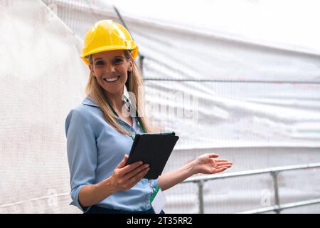 Smiling engineer gesturing holding tablet PC Stock Photo