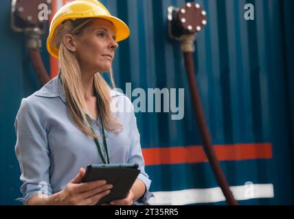Contemplative engineer wearing hardhat holding tablet PC Stock Photo