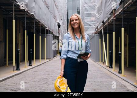 Happy blond engineer standing at construction site Stock Photo
